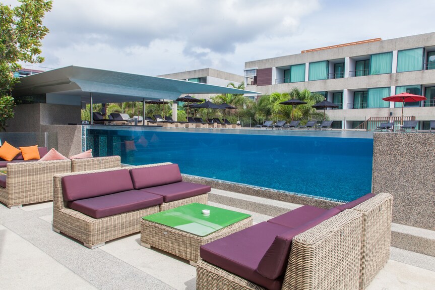 Hotel pool behind a glass wall with wicker lounge seating