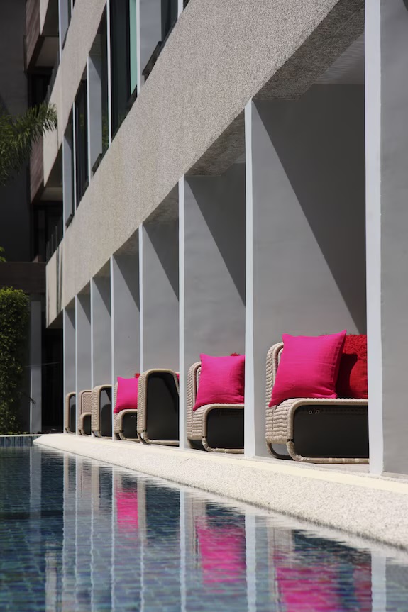 Row of chairs with pink pillows along the pool channel